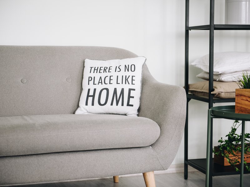 grey sofa with white pillow and black shelf